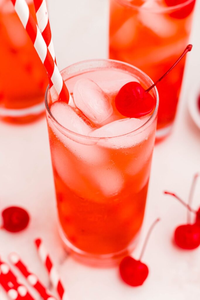 Bright red drink with ice and a red straw, topped with a cherry. 