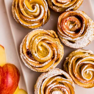 Apple roses on a white rectangle plate, then sprinkled with powdered sugar.