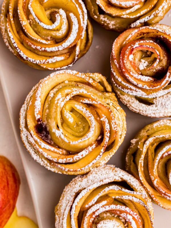 Apple roses on a white rectangle plate, then sprinkled with powdered sugar.