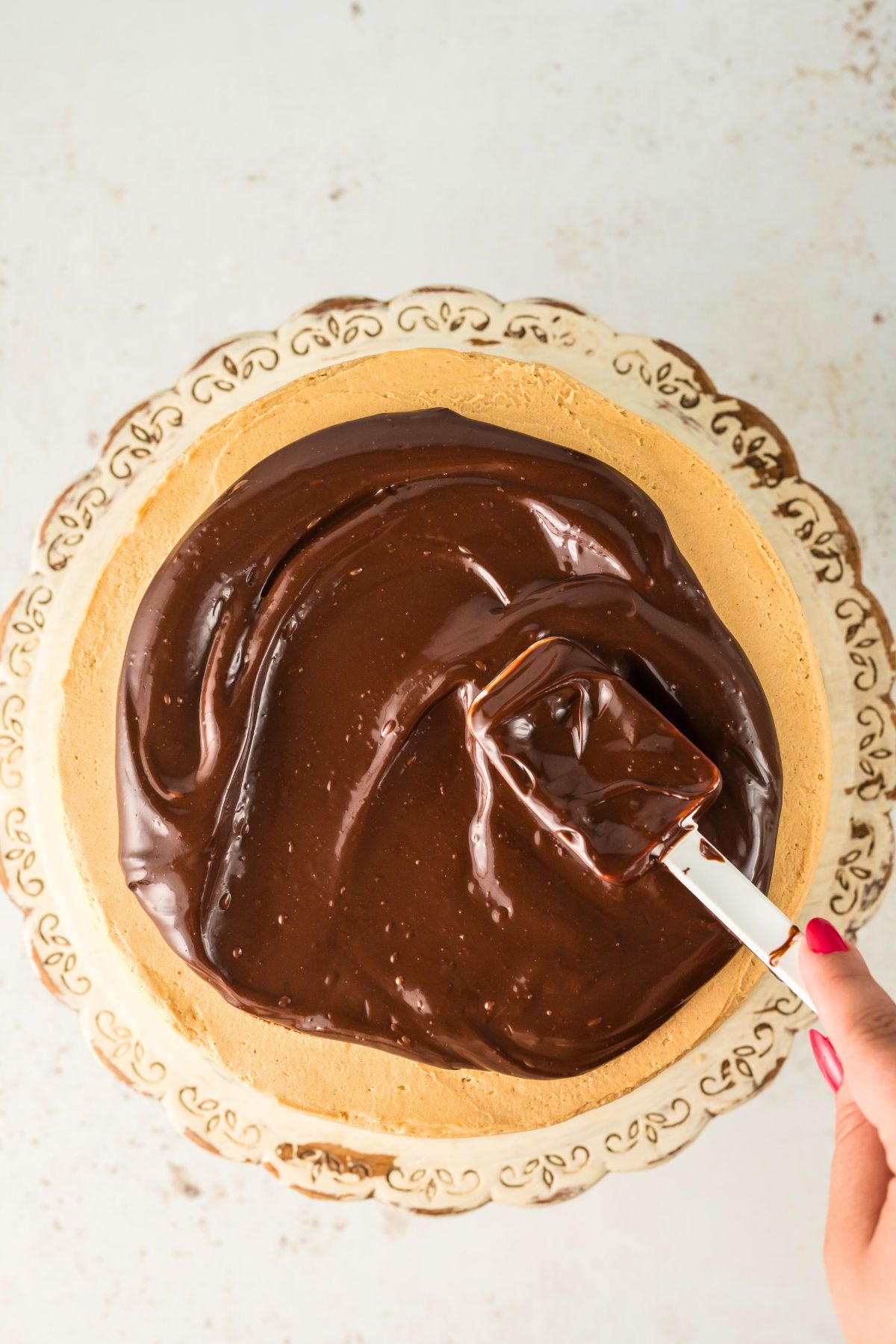 Melted chocolate ganache on top of a frosted chocolate cake. 