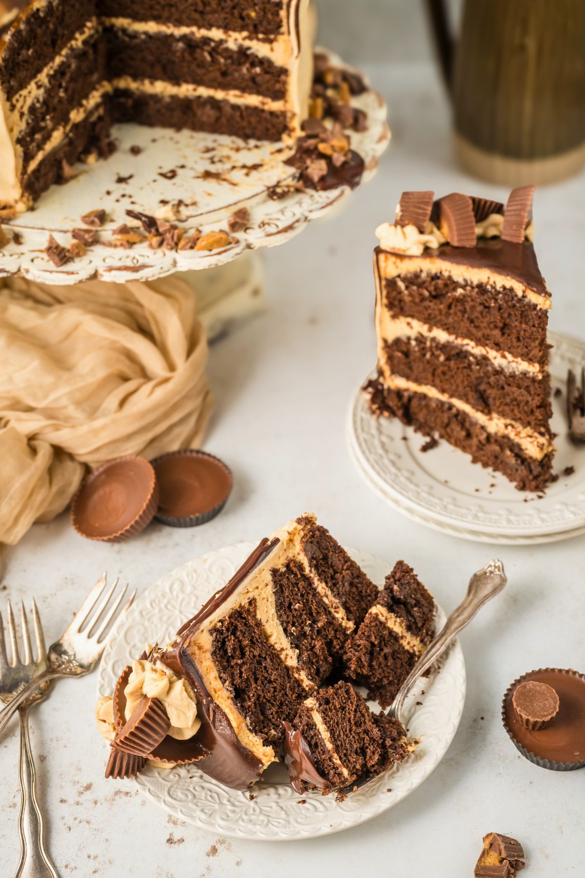 Sliced of cake on small white plates in front of the whole cake on a pedestal. 