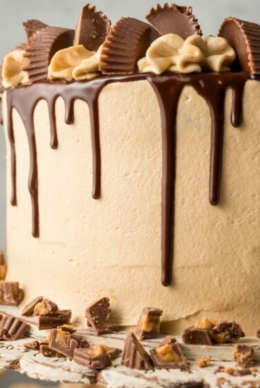 Chocolate cake covered in peanut butter frosting with a chocolate ganache drizzle down the sides.