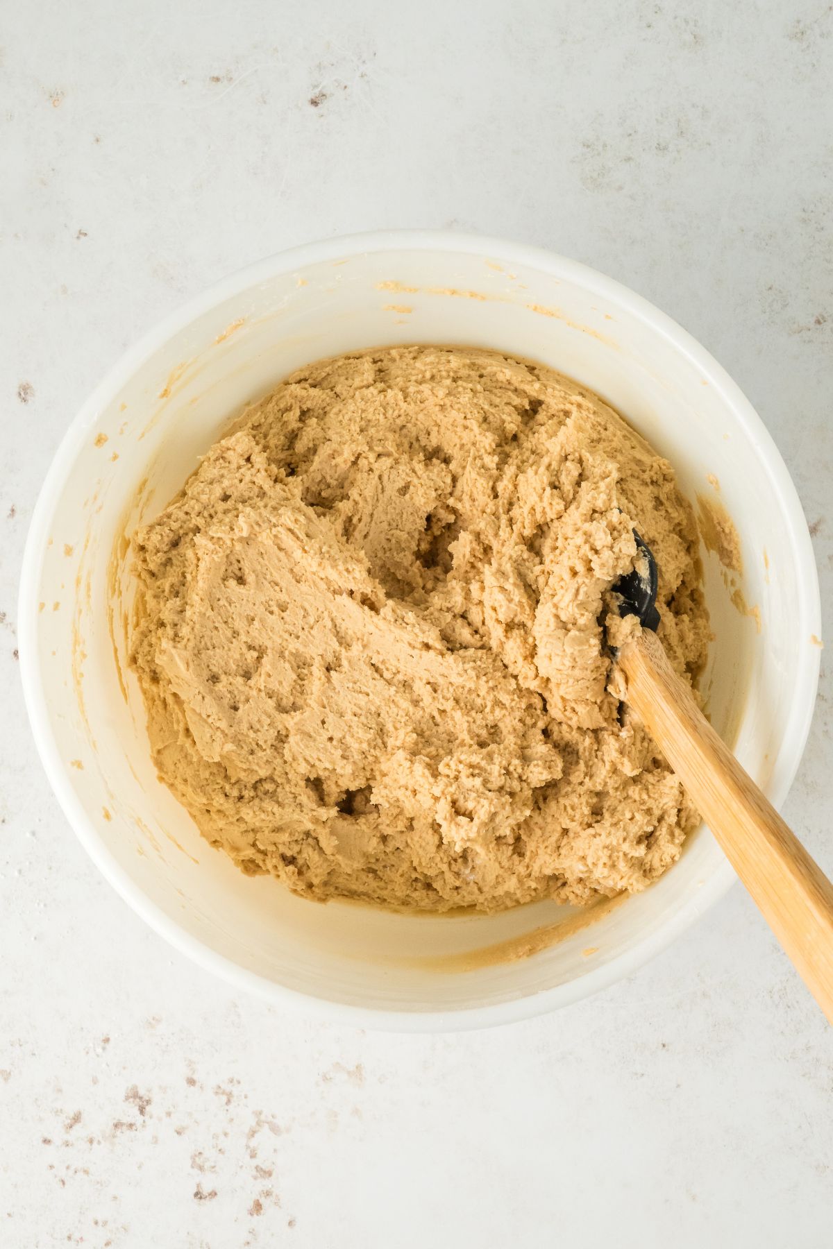 Creamy peanut butter frosting being mixed in a white bowl. 