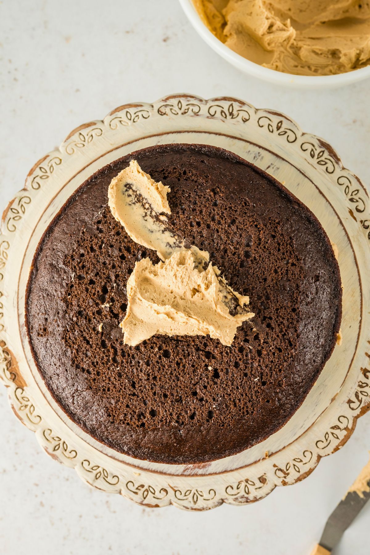 Peanut butter frosting on top of a chocolate cake, before spreading over the entire cake. 