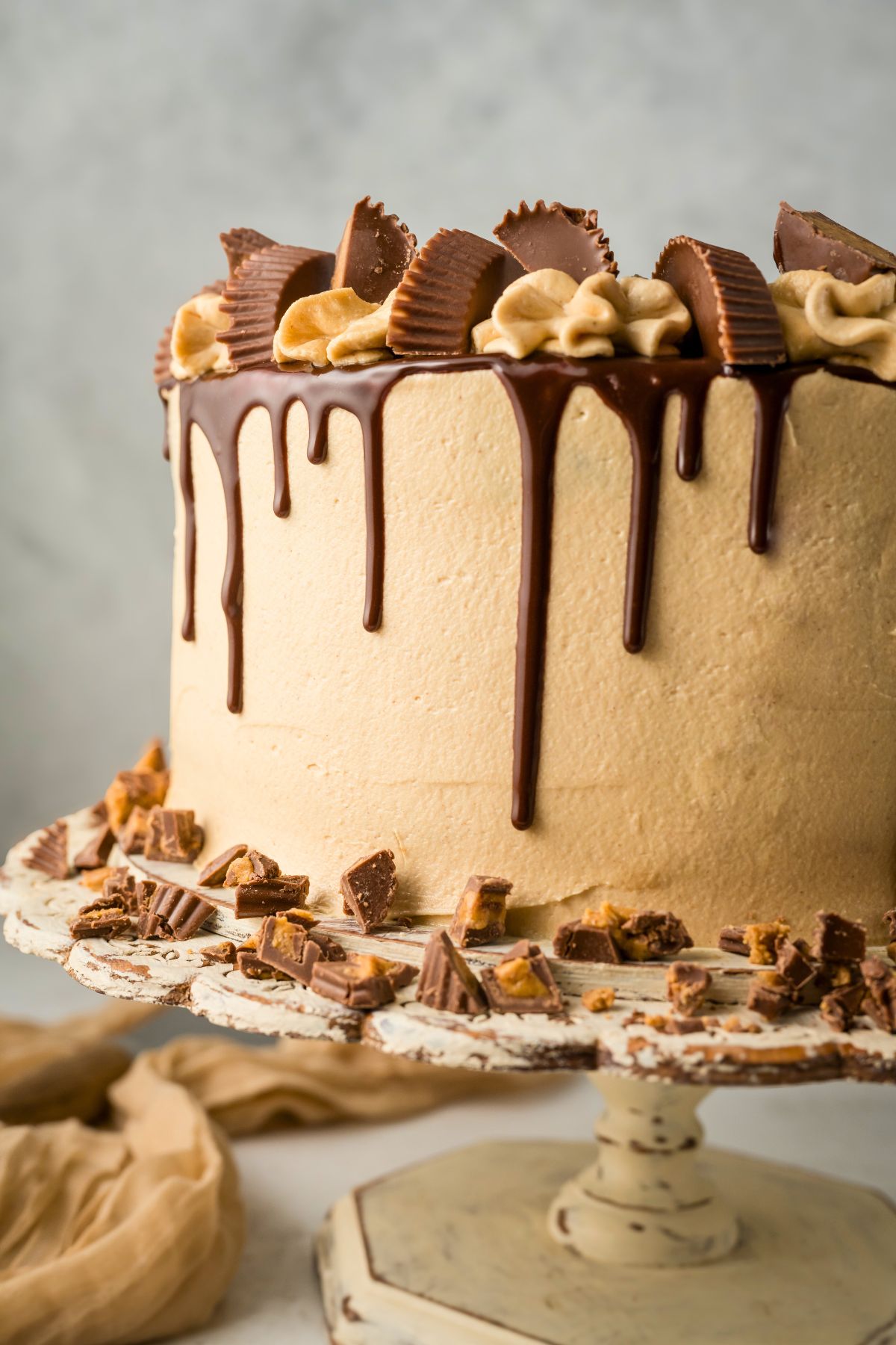 Chocolate cake covered in peanut butter frosting with a chocolate ganache drizzle down the sides. 