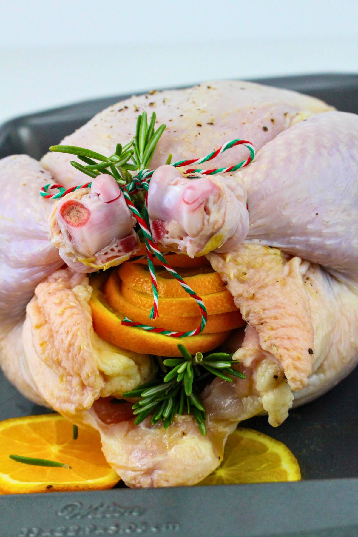 Uncooked chicken stuffed with orange slices and seasonings, then trussed. 