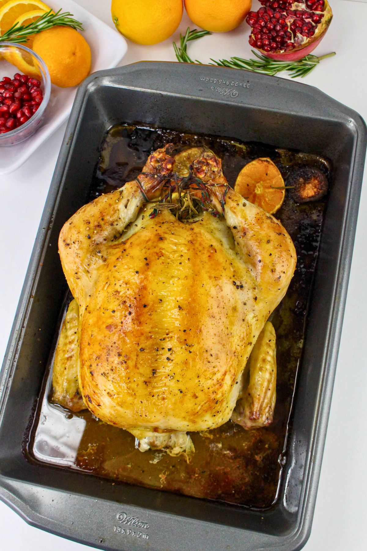 Golden juicy roasted chicken in a roasting pan with juices. 