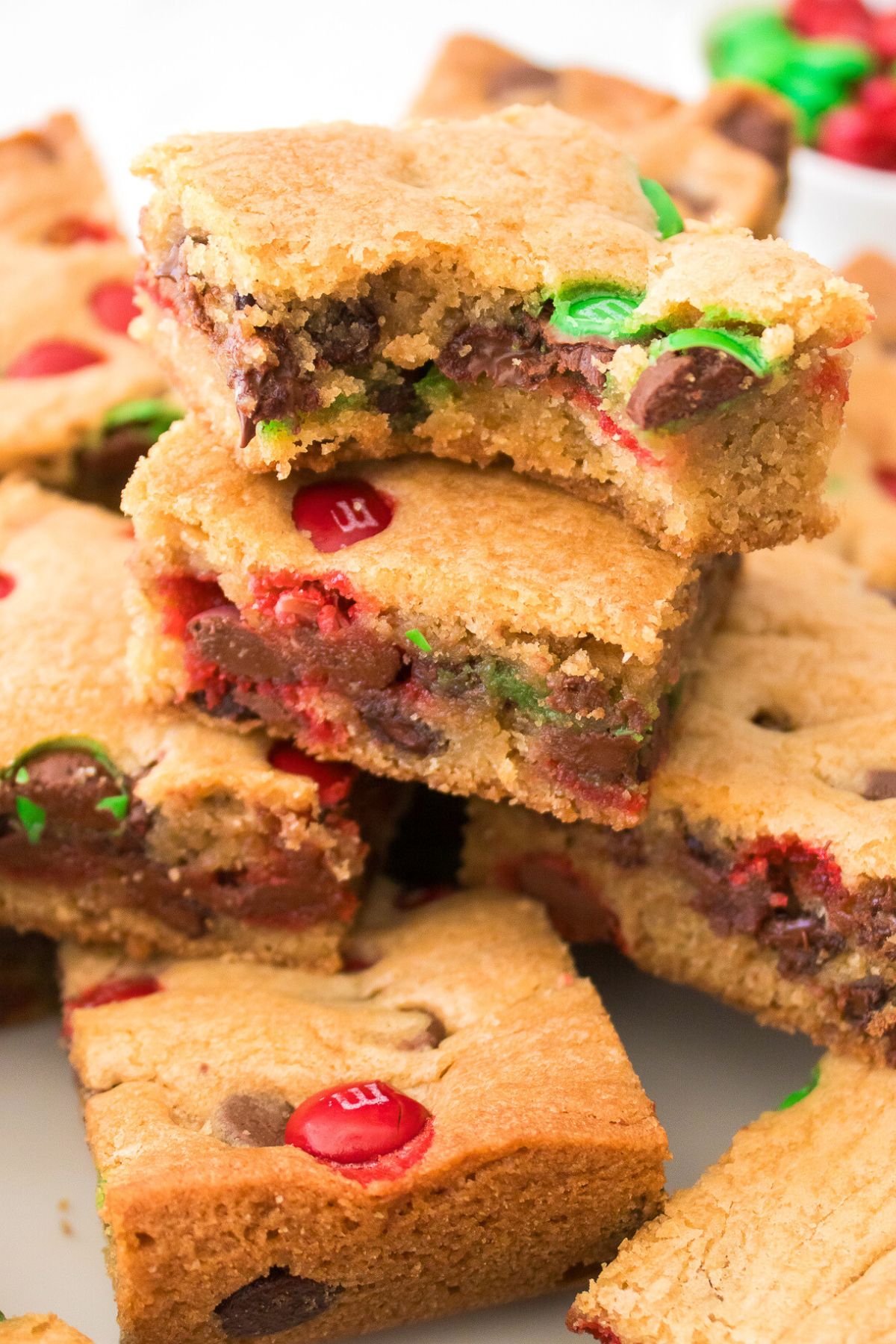 Golden cookie bars stacked on a plate, with red and green m and m's inside. 