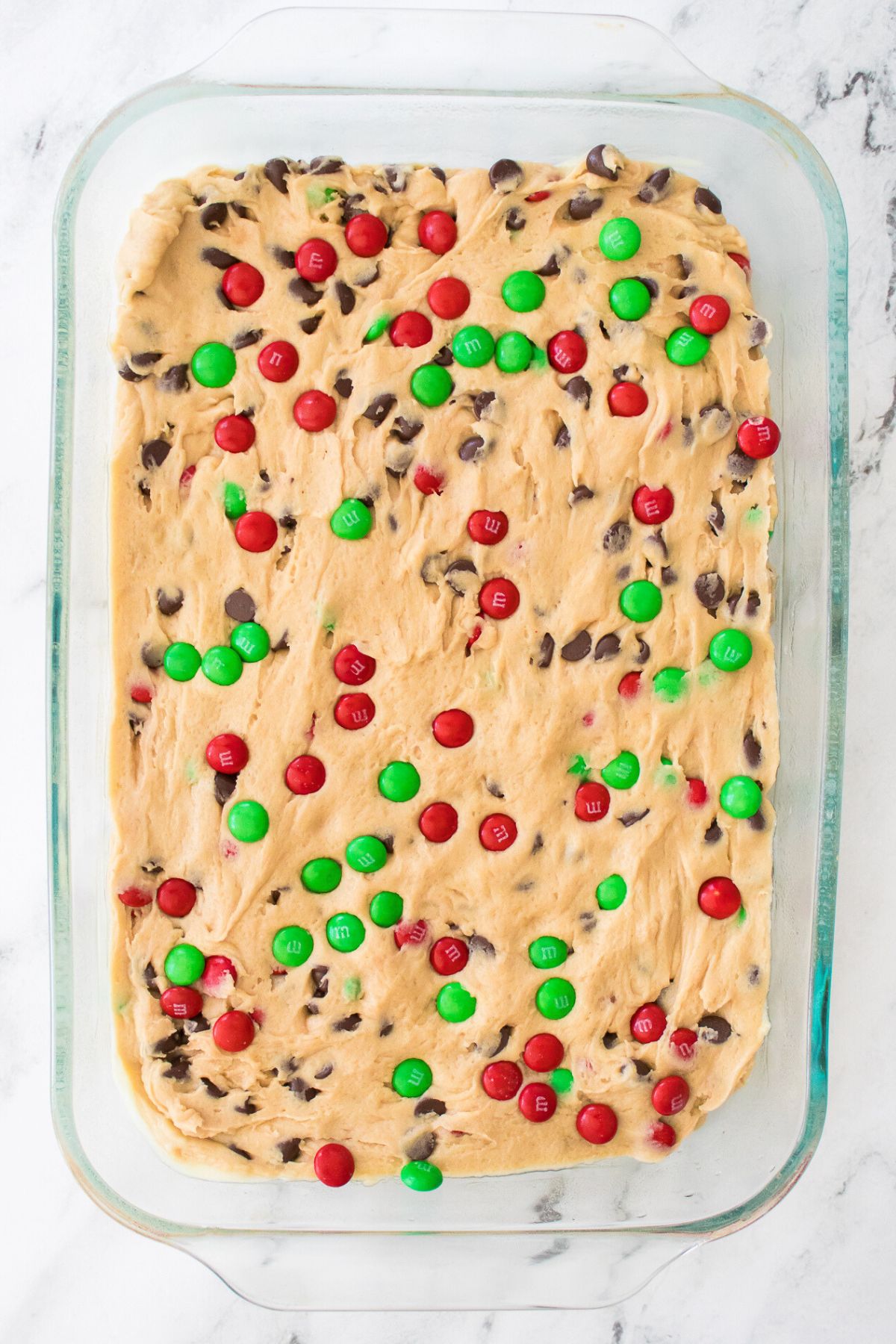 Uncooked dough spread into a clear glass baking dish. 