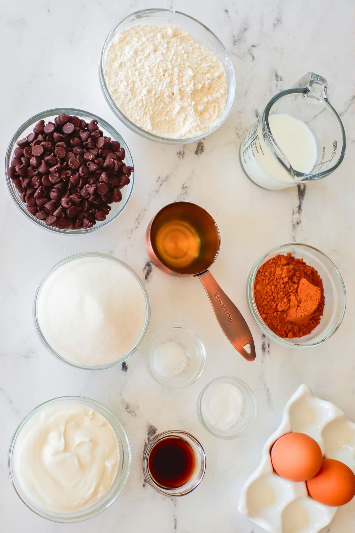 Ingredients measured in clear glass bowls on a marble table. 