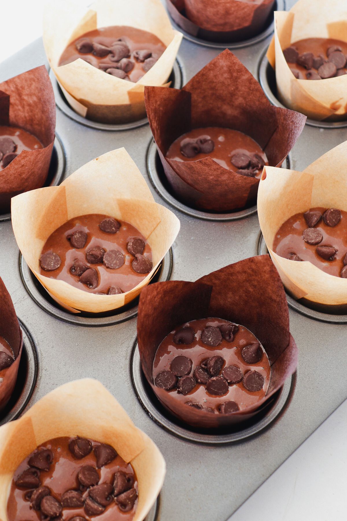 Uncooked double chocolate chip batter in a paper liners in muffin tin. 