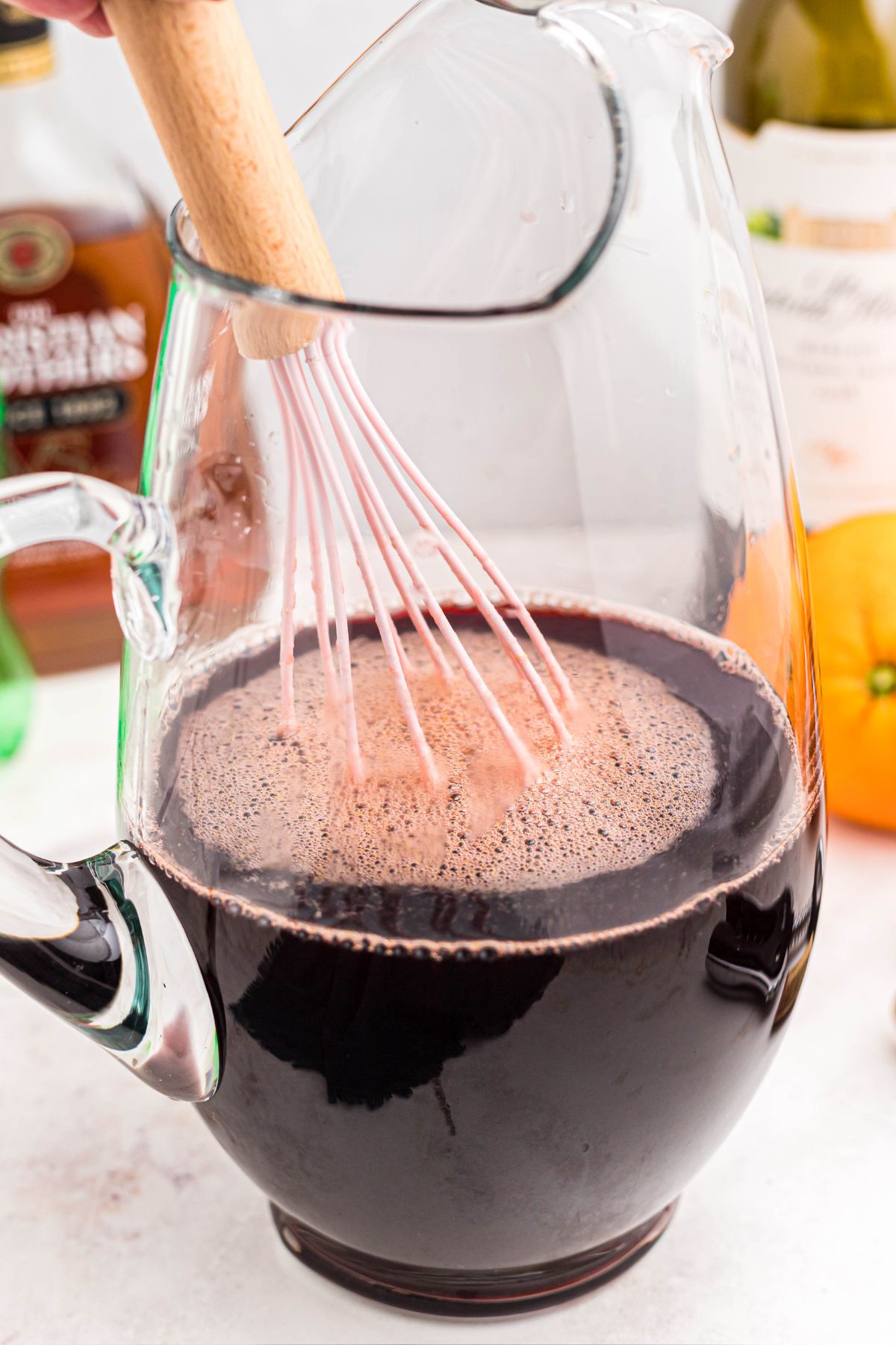 Sangria mixture being stirred together in a clear glass pitcher. 