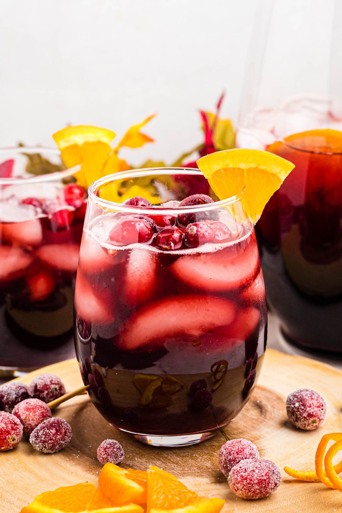 Stemless wine glass filled with fall sangria, topped with cranberries and orange slices. 