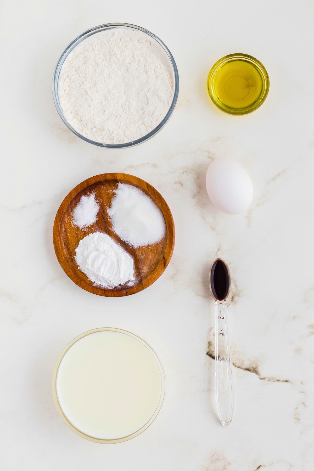 Ingredients measured out in glass containers on a marble table. 