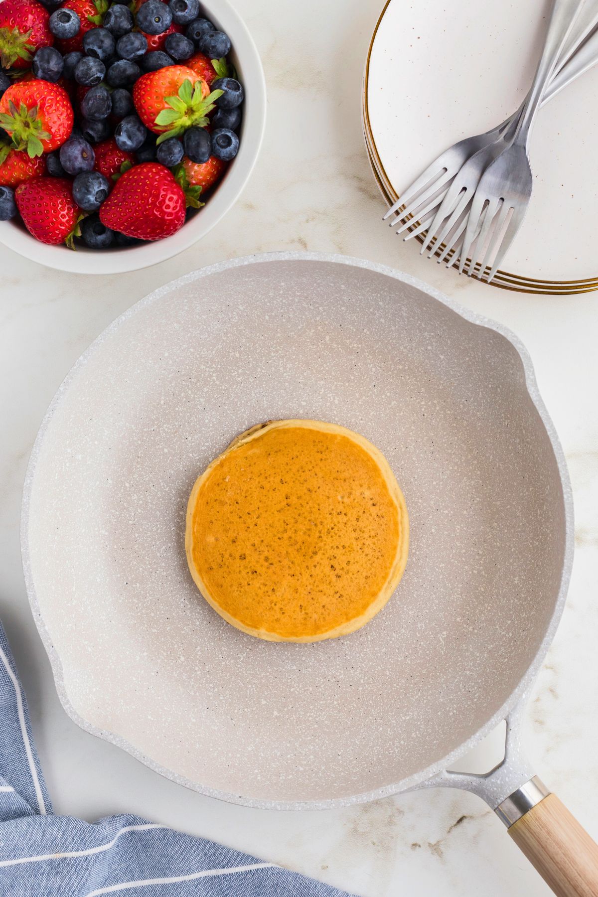 Golden fluffy pancake in the middle of the skillet after being cooked.