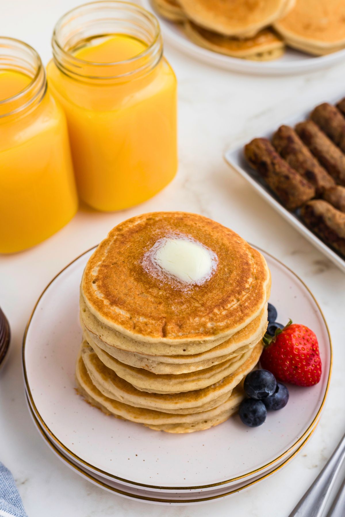 Golden gluten free pancakes stacked on a white plate. 