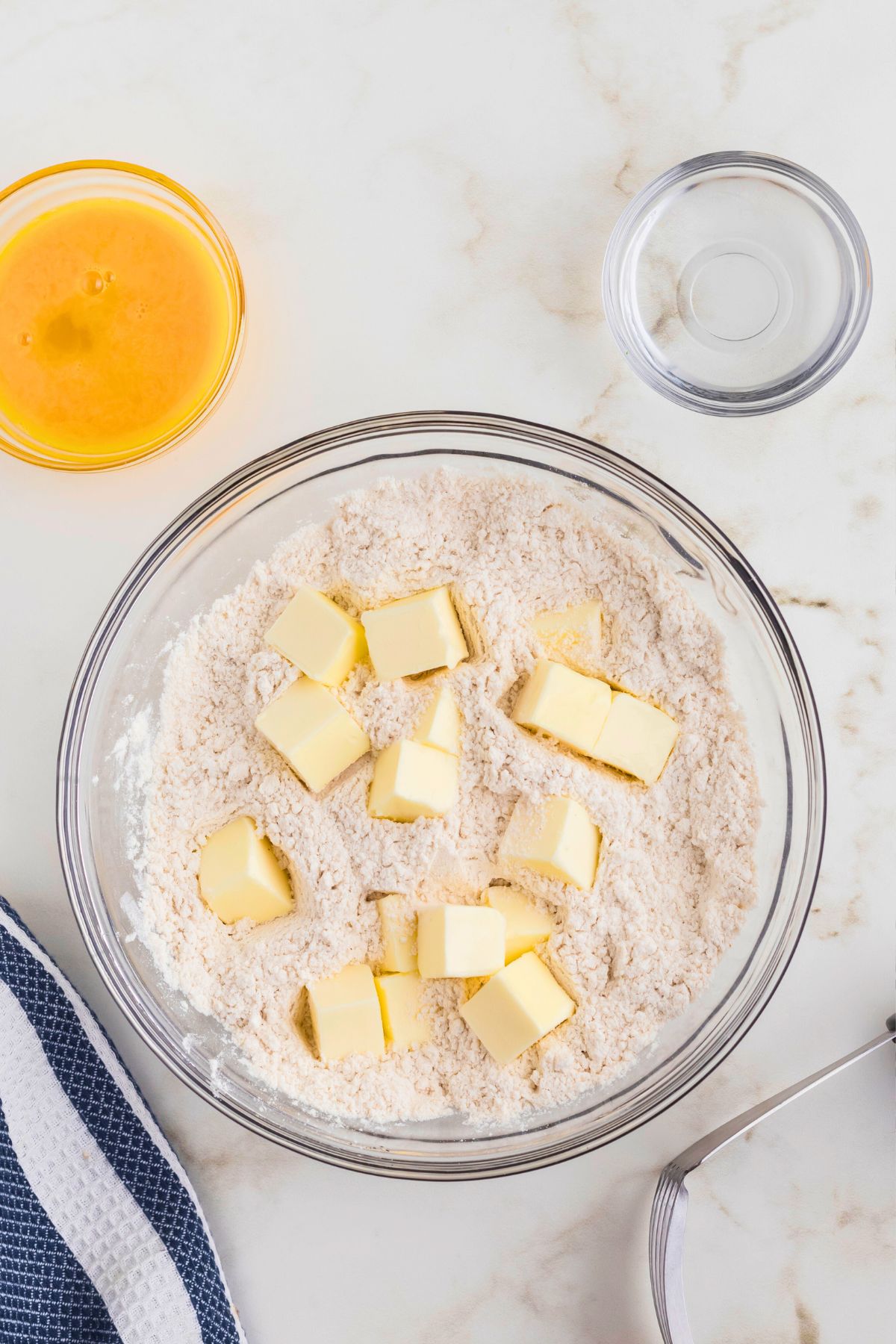 Cold cubes of butter in a clear glass bowl before mixing with the dry ingredients. 