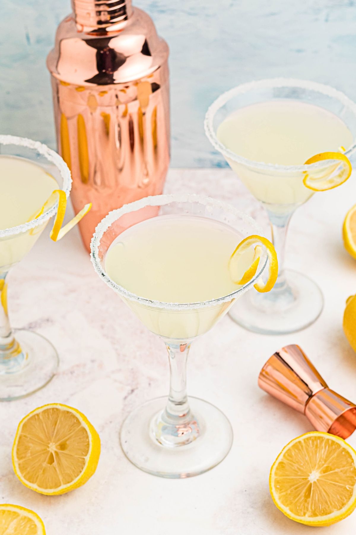 Lemon drop martinis on a marble board, surrounded by lemon slices. 