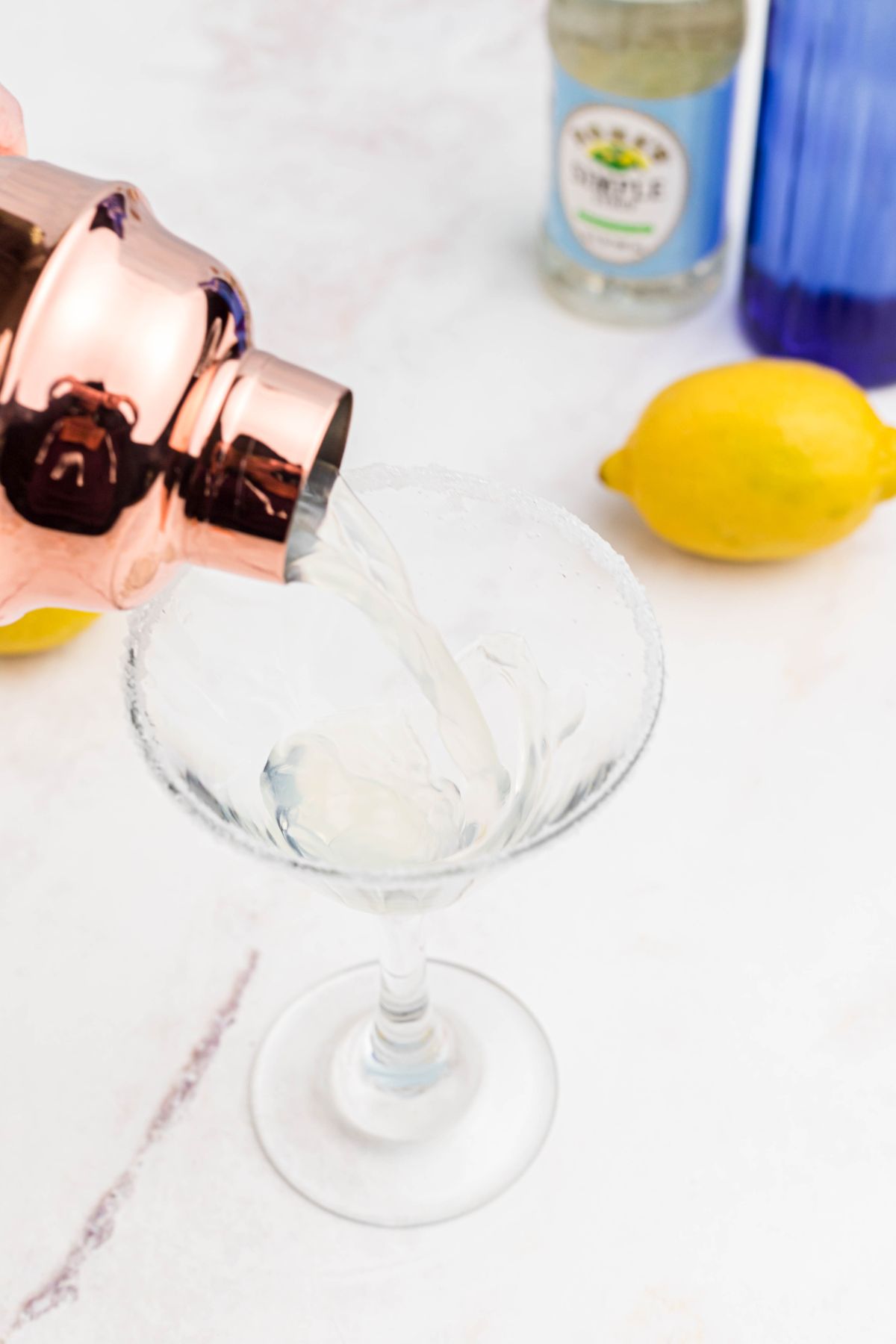 Vodka and simply syrup mixture being poured in a martini glass. 