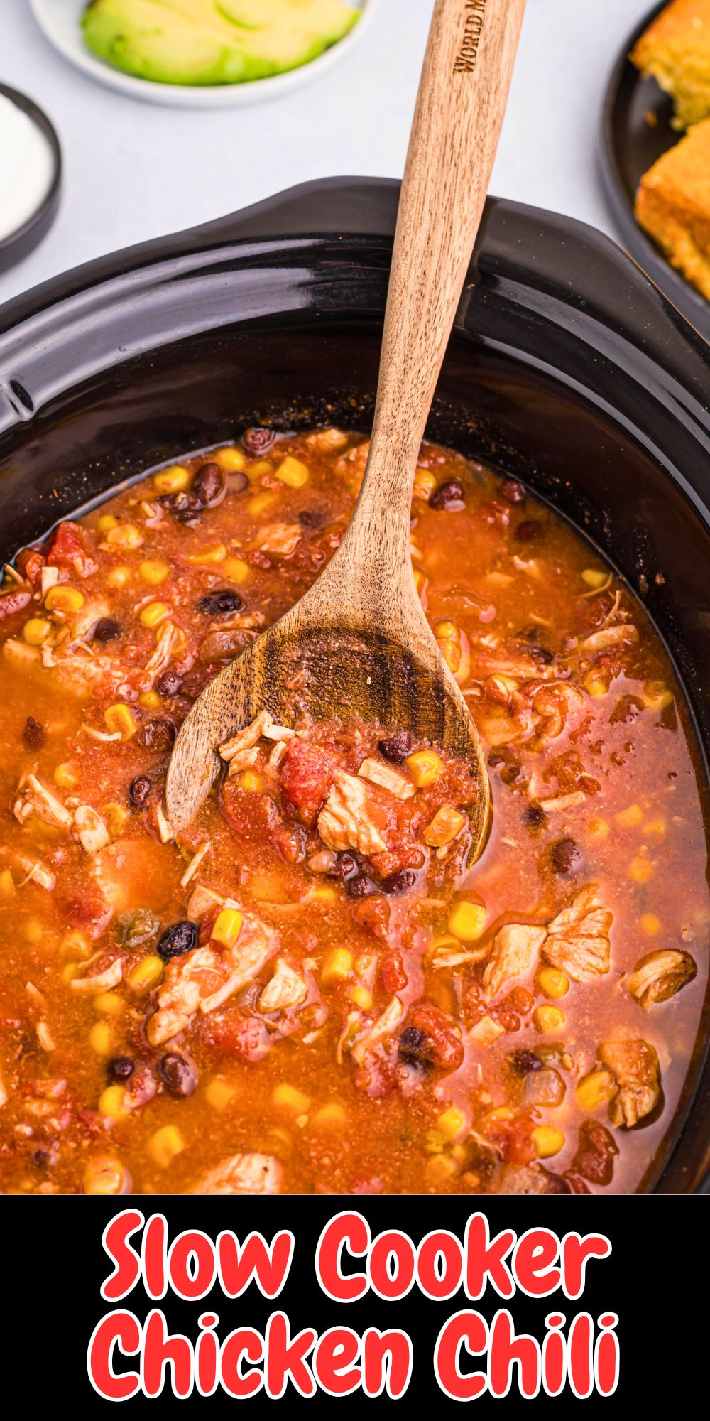 Slow cooker chicken chili in a crock pot ceramic bowl with a wooden spoon serving it.