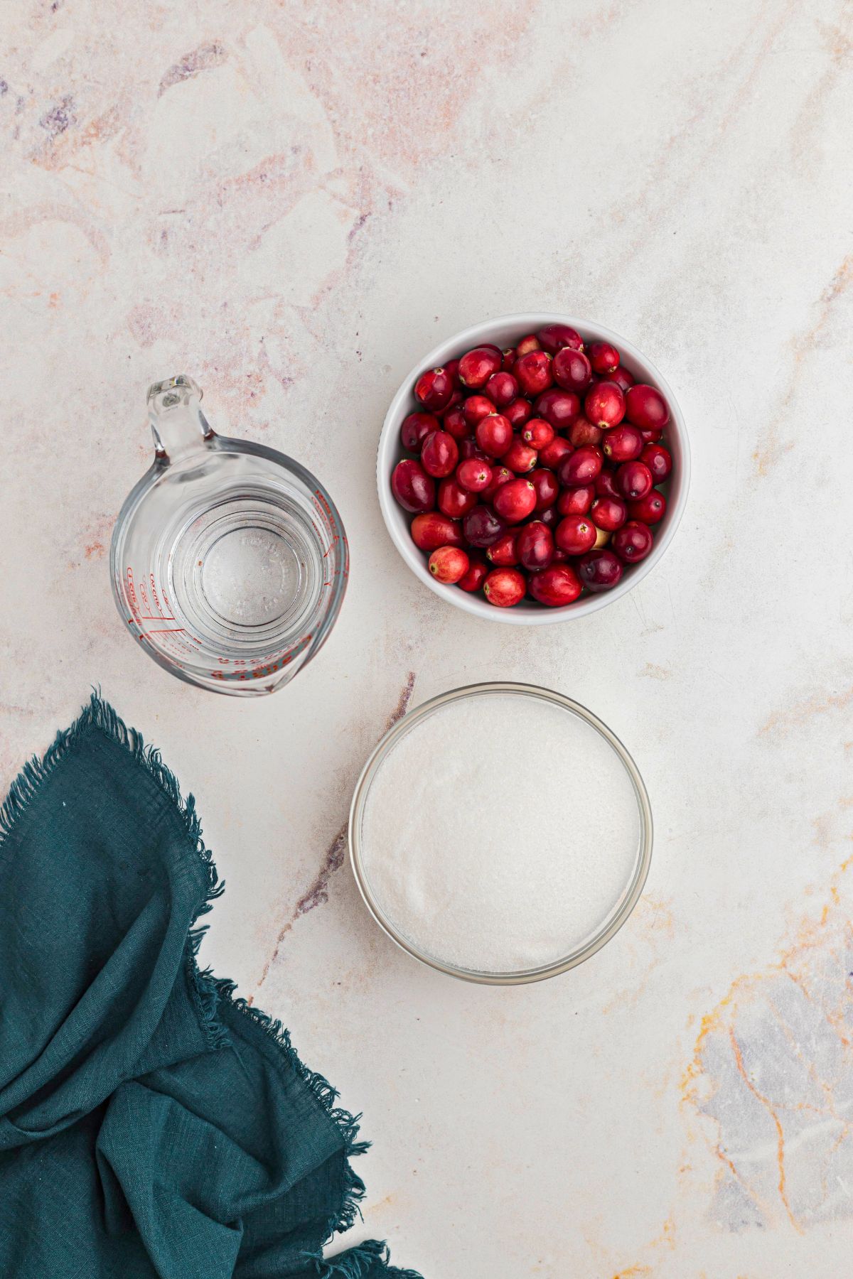 Ingredients needed to make sugared cranberries on a marble table. 