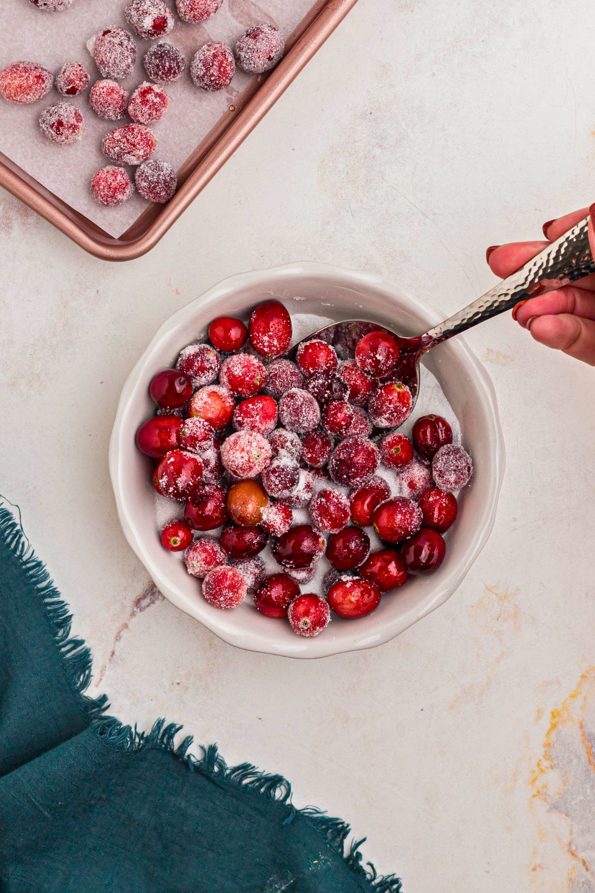 Syrup coated cranberries being rolled in a bowl a sugar to coat them. 