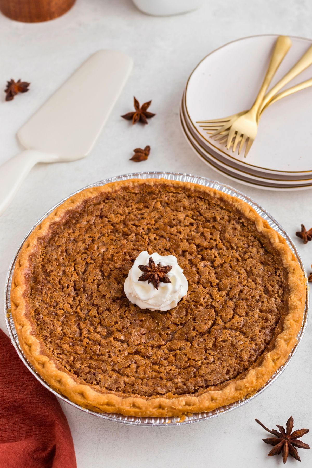 Whole sweet potato pie topped with whipped cream on a marble table. 