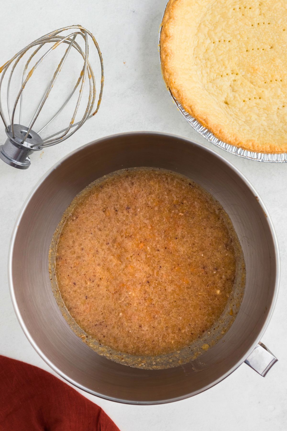 Mashed sweet potatoes mixed with other ingredients in a silver mixing bowl. 