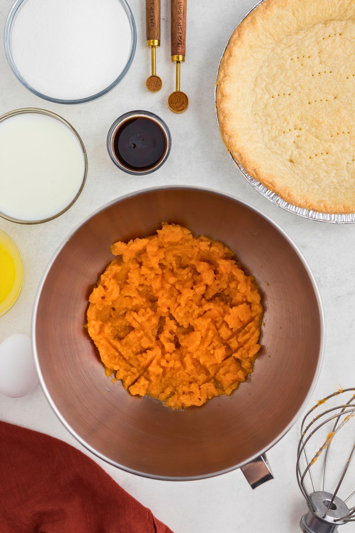 Sweet potatoes mashed in a silver mixing bowl. 