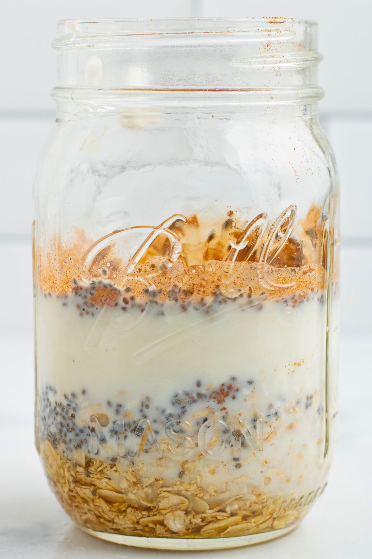 Layers of oats, yogurt, and fruit, in a clear mason glass. 