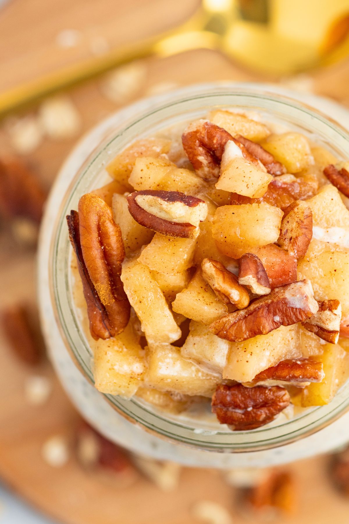 Overhead photo of apple pie overnight oats in a mason jar, topped with chopped apples and nuts. 