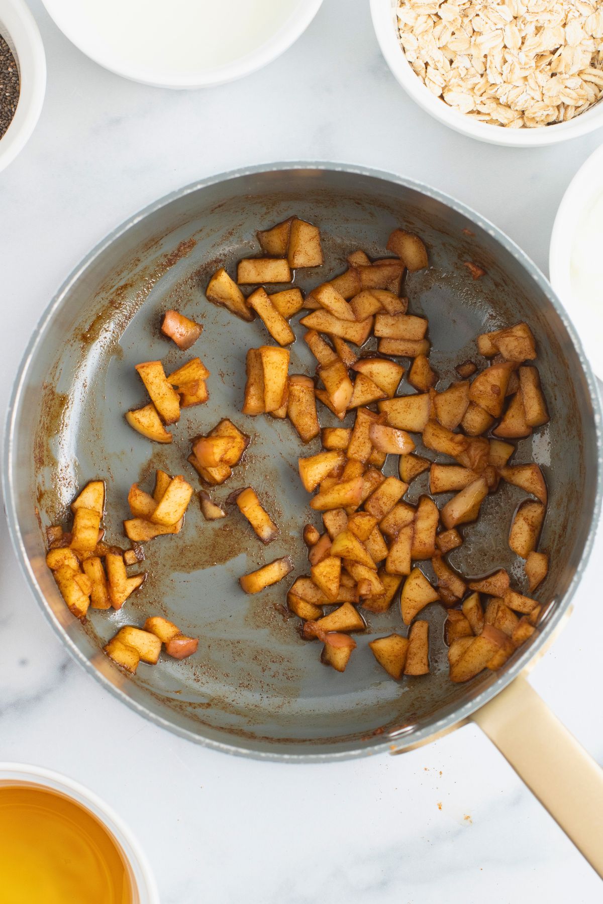 Cooked apples in a saucepan, coated with spices. 