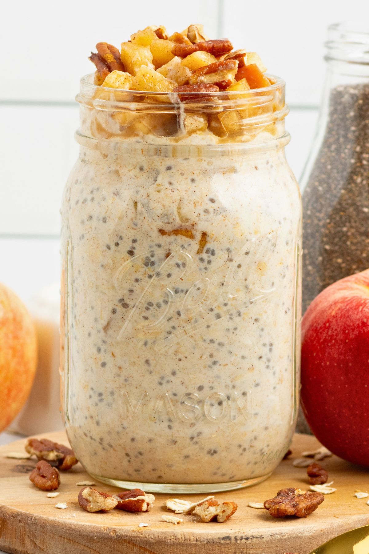 Creamy yogurt mixed with oats and apple slices in a mason jar making apple pie overnight oats. 