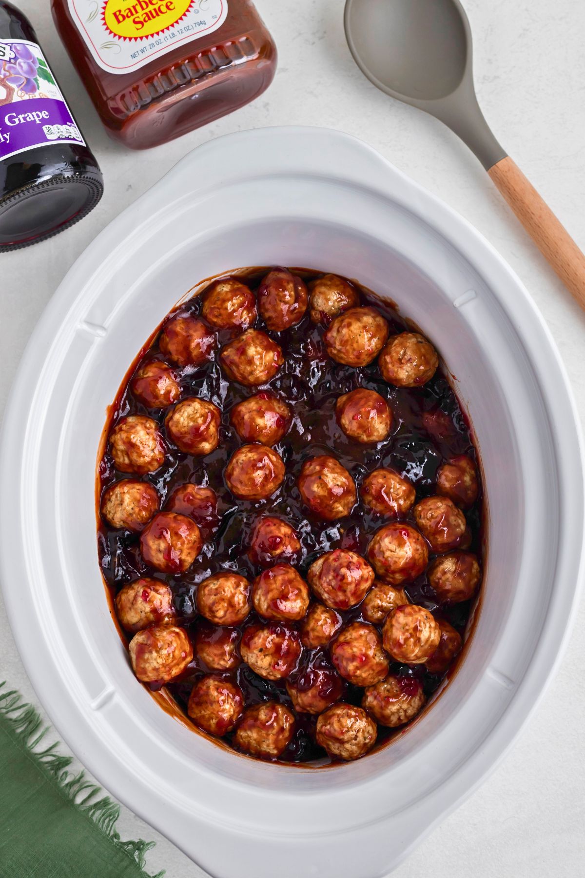 Grape jelly meatballs being cooked in a crock pot. 