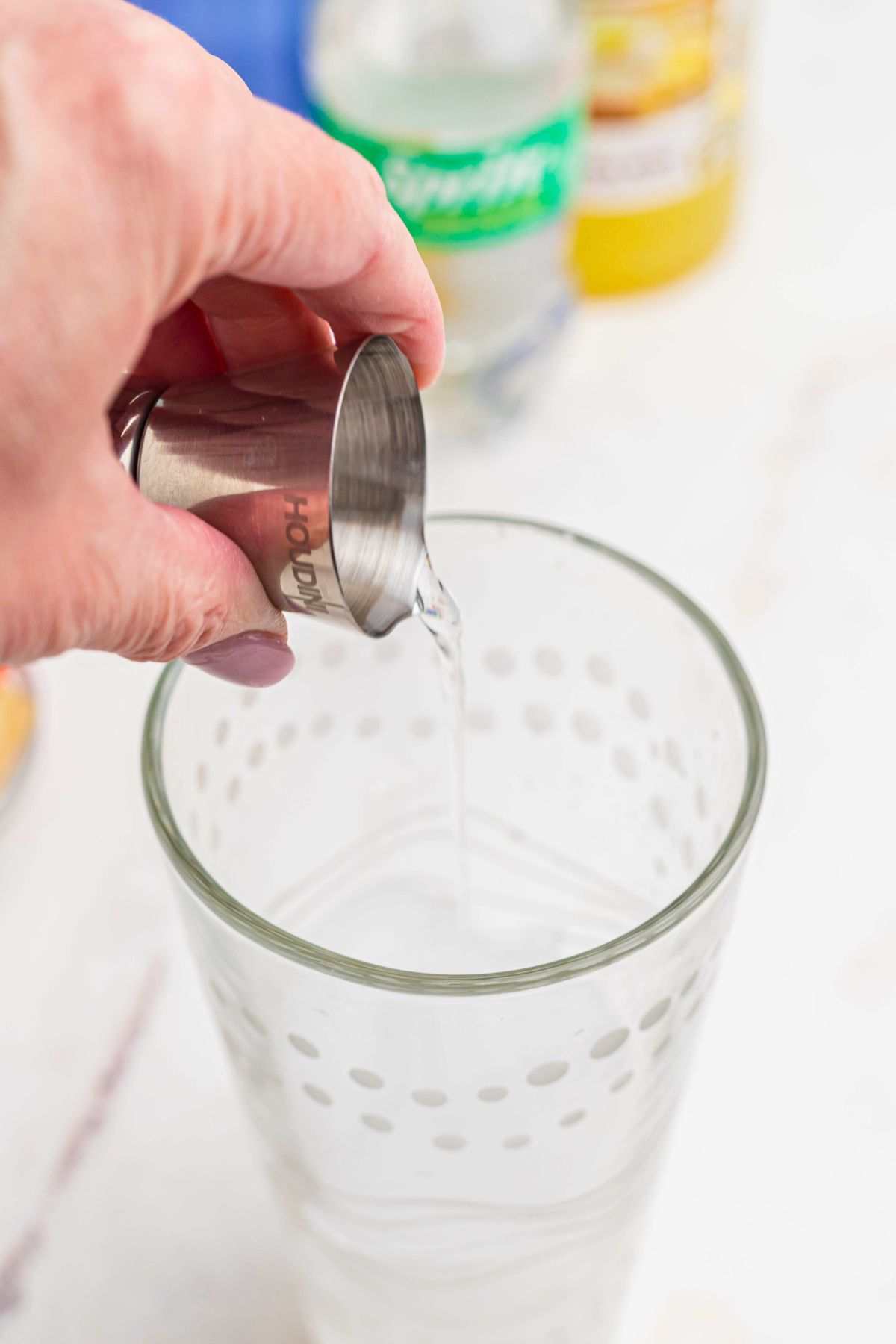 Vodka being measured into a clear cocktail shaker. 