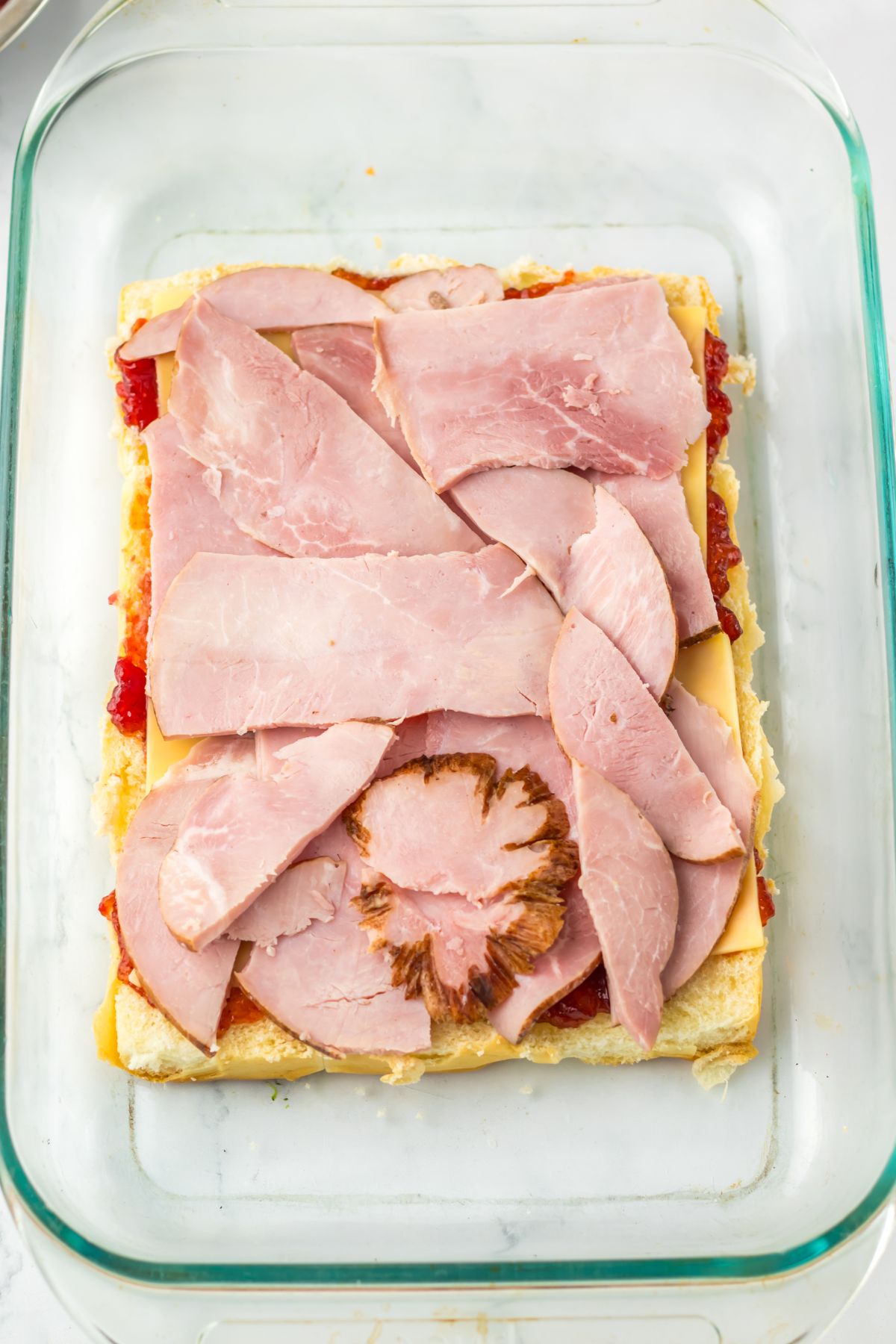 Slices of ham on top of Hawaiian rolls.