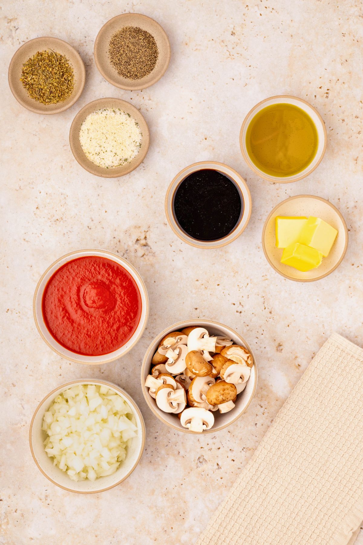 Ingredients needed to make meatloaf measured in small glass bowls on a marble table. 