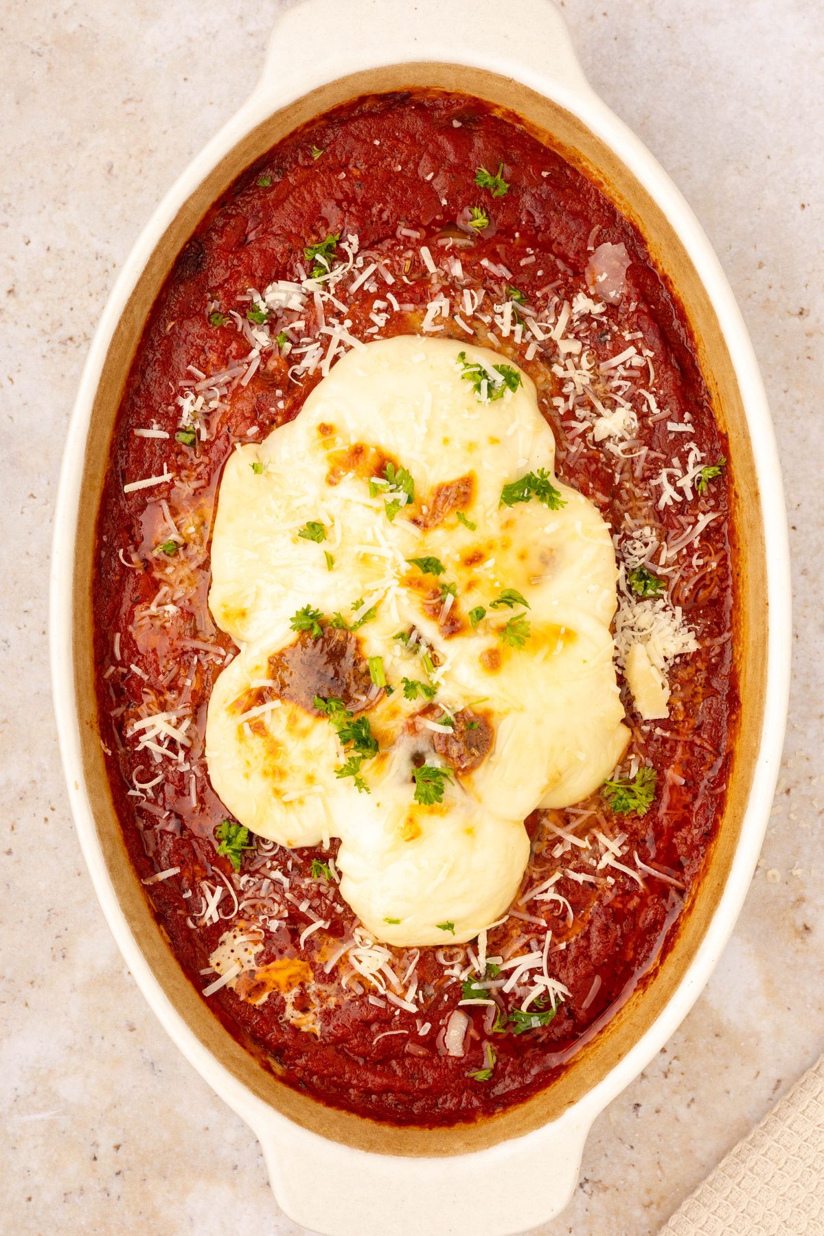 Italian meatloaf in an oval casserole dish, topped with mozzarella cheese and marinara sauce