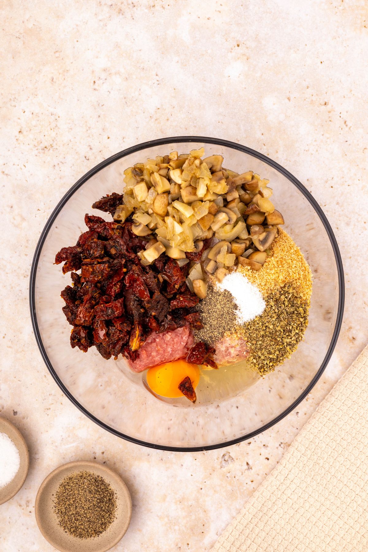 Meatloaf ingredients being mixed in a clear glass bowl. 