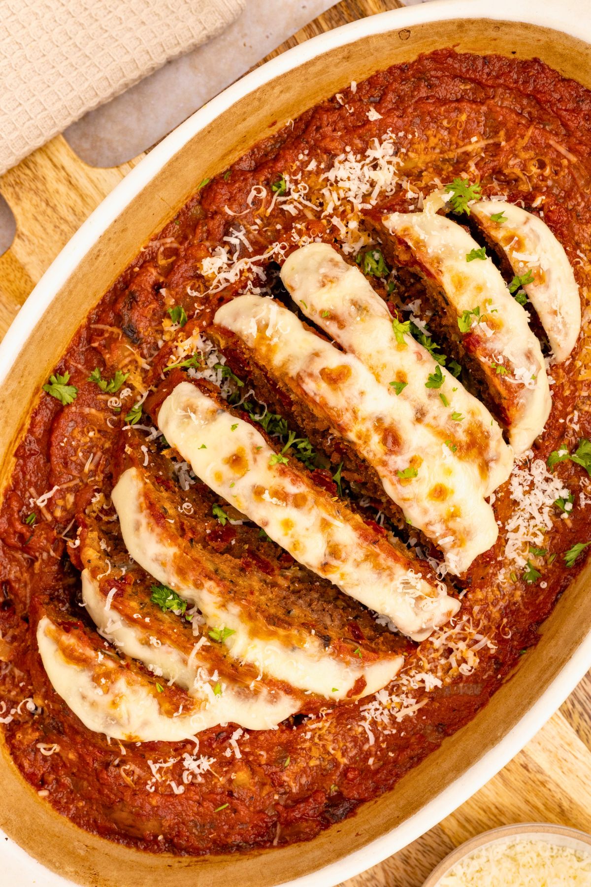 Italian meatloaf in an oval casserole dish, topped with mozzarella cheese and marinara sauce