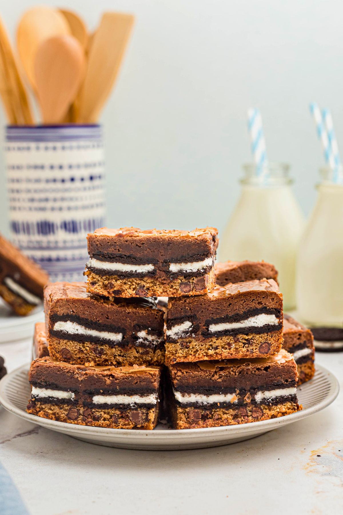 Golden slutty brownies stacked on a white plate with milk in the background. 