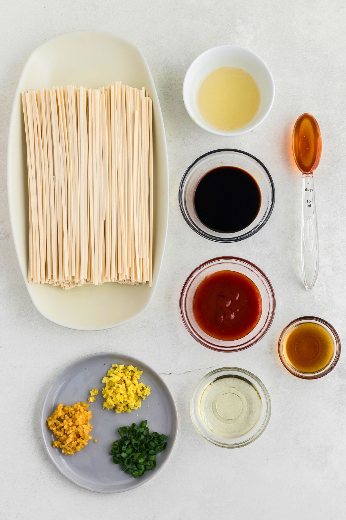 Ingredients needed to make spicy noodles measured on a white marble table. 