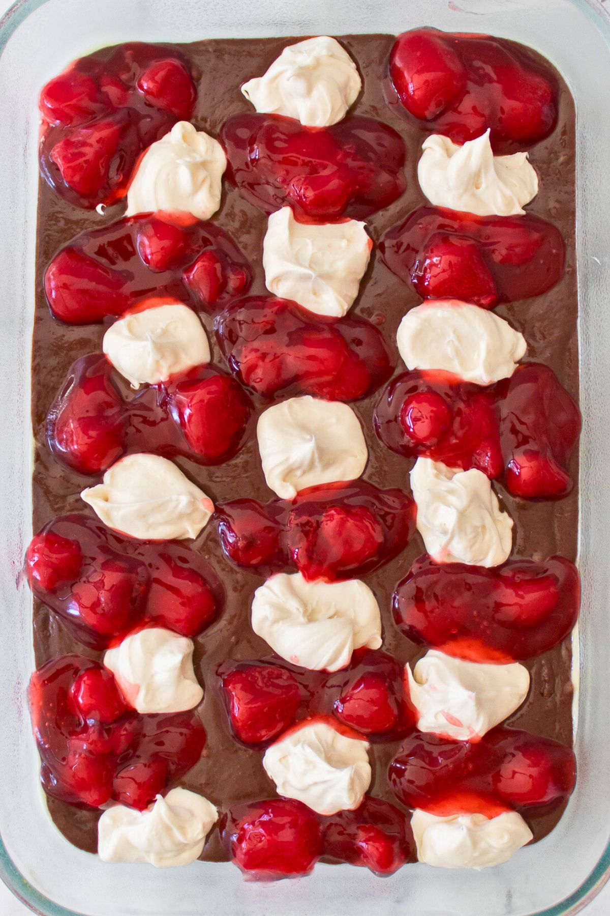 Strawberry pie filling dropped in spoonfuls in between cheesecake spoonfuls over the brownie batter. 