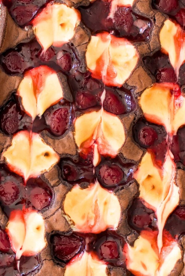 Baked strawberry cheesecake swirled together on top of brownies in a glass dish.