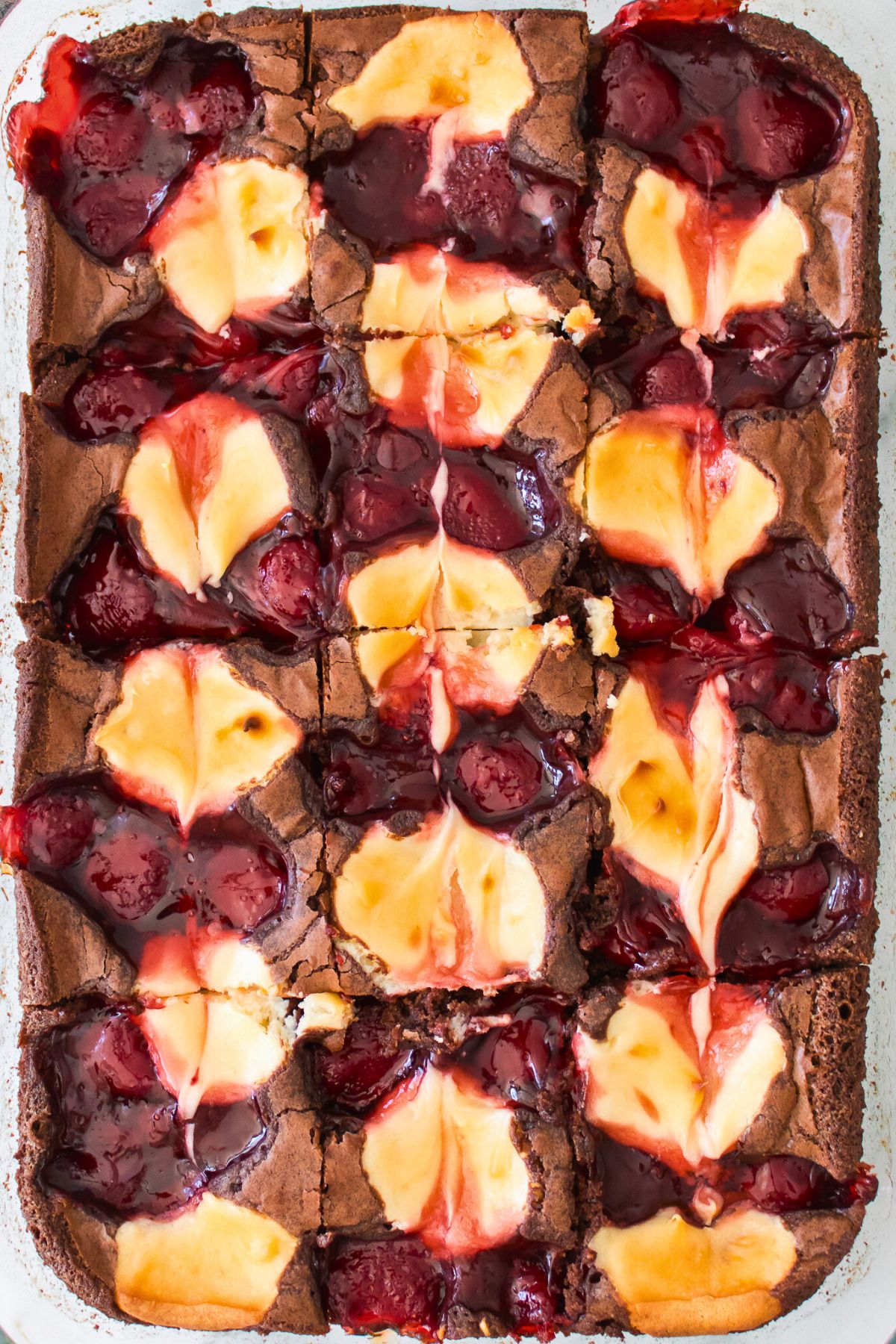 Baked strawberry cheesecake swirled together on top of brownies in a glass dish. 