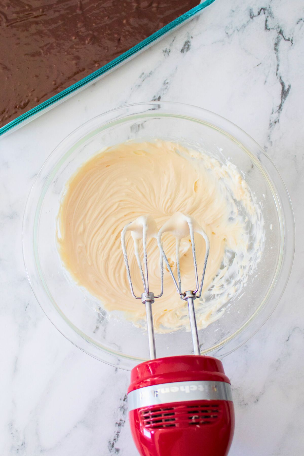 Smooth and creamy cream cheese and powdered sugar mixture in a clear glass bowl. 