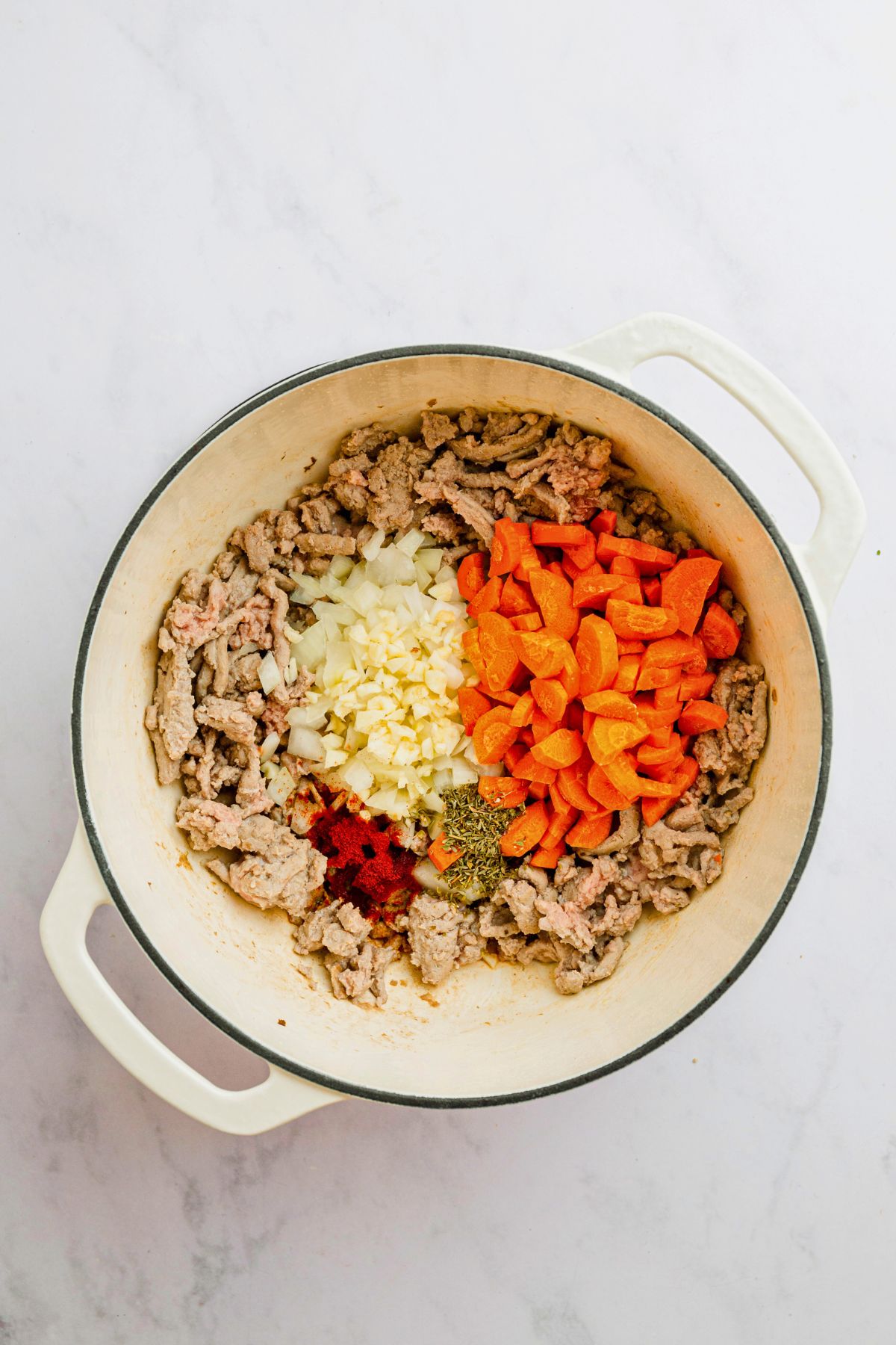 Ground turkey and veggies in a stock pot before adding other ingredients to make cabbage roll soup.