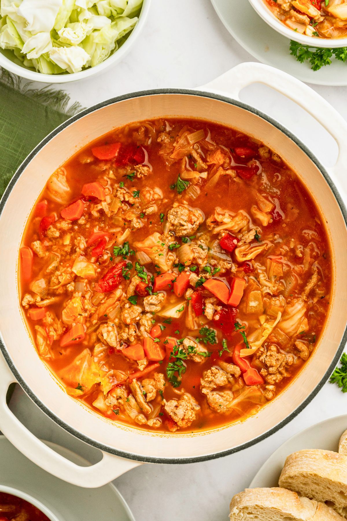 Cabbage roll soup in a white stock pot topped with chopped parsley. 