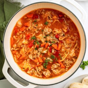 Cabbage roll soup in a white stock pot topped with chopped parsley.