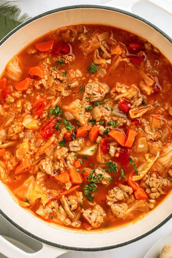 Cabbage roll soup in a white stock pot topped with chopped parsley.